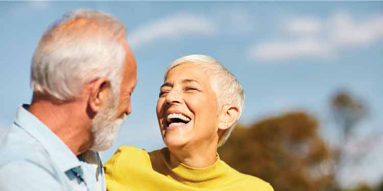 Couple with grey hair looking at each other, smiling.